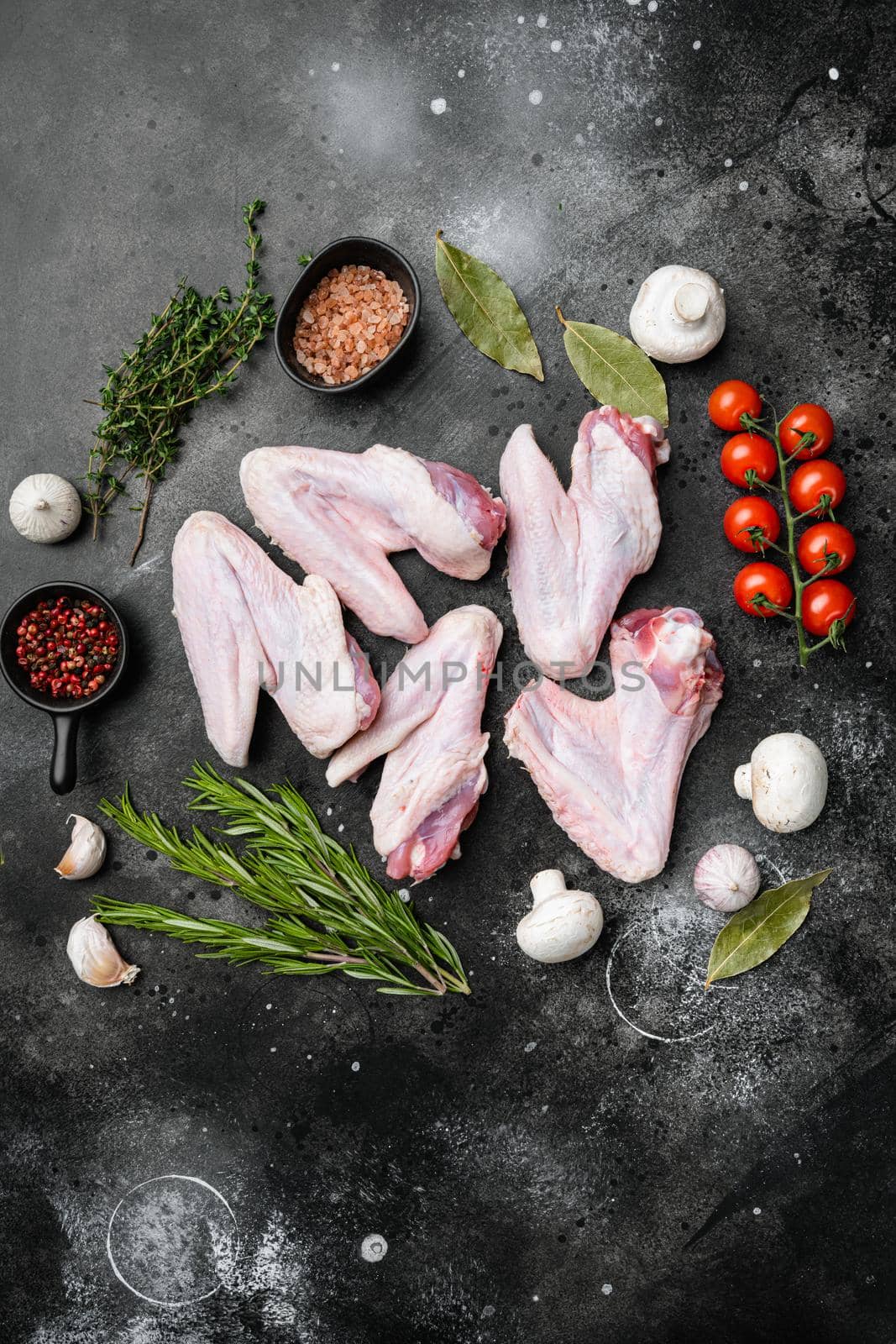 Raw goose wings set, on black dark stone table background, top view flat lay, with copy space for text