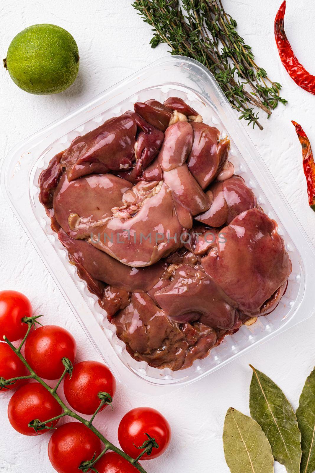 Poultry offal Chicken liver in a plastic container set, on white stone table background, top view flat lay