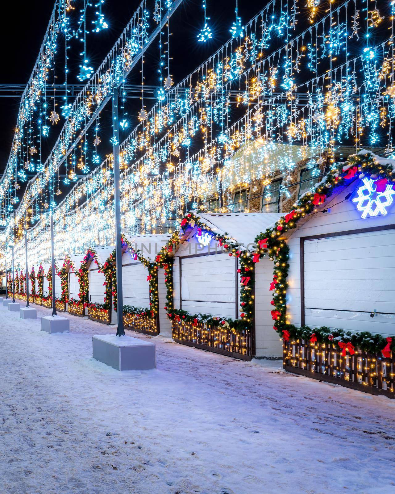 Christmas or New Year's market in a European city with houses decorated with toy balls and garlands at night.