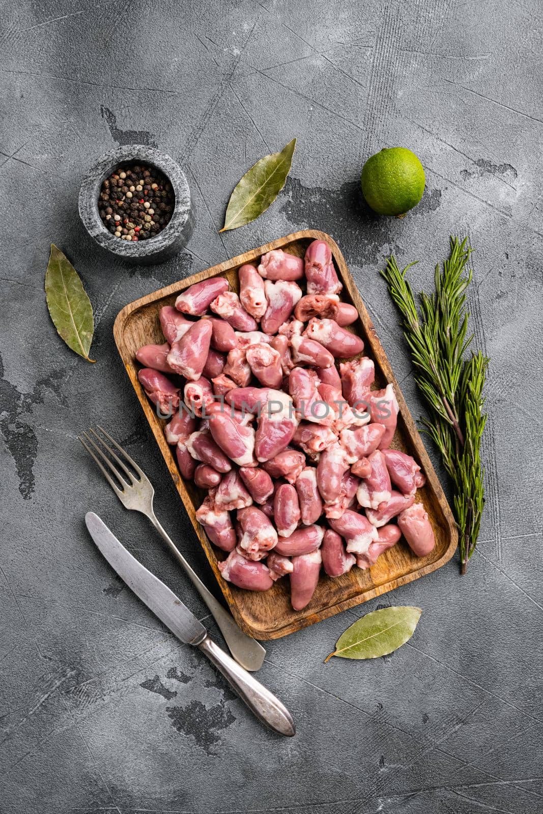 Raw uncooked chicken gizzards, chicken hearts set, on gray stone table background, top view flat lay