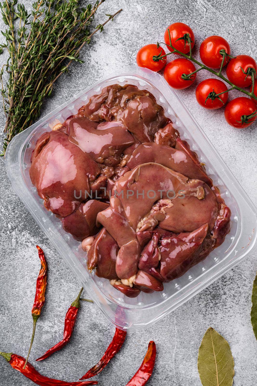 Poultry offal Chicken liver in a plastic container set, on gray stone table background, top view flat lay