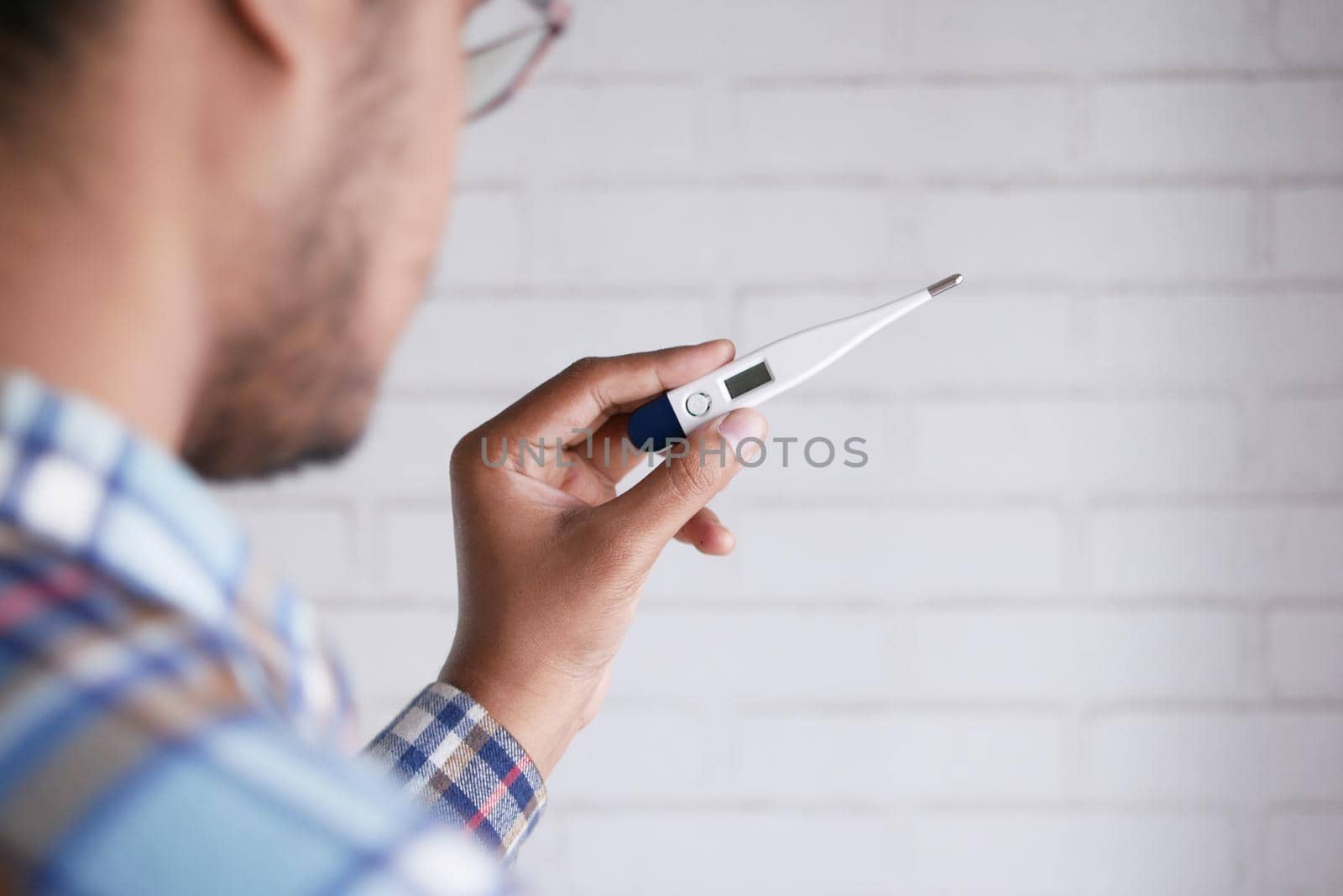 rear view of man hand hold a digital thermometer .