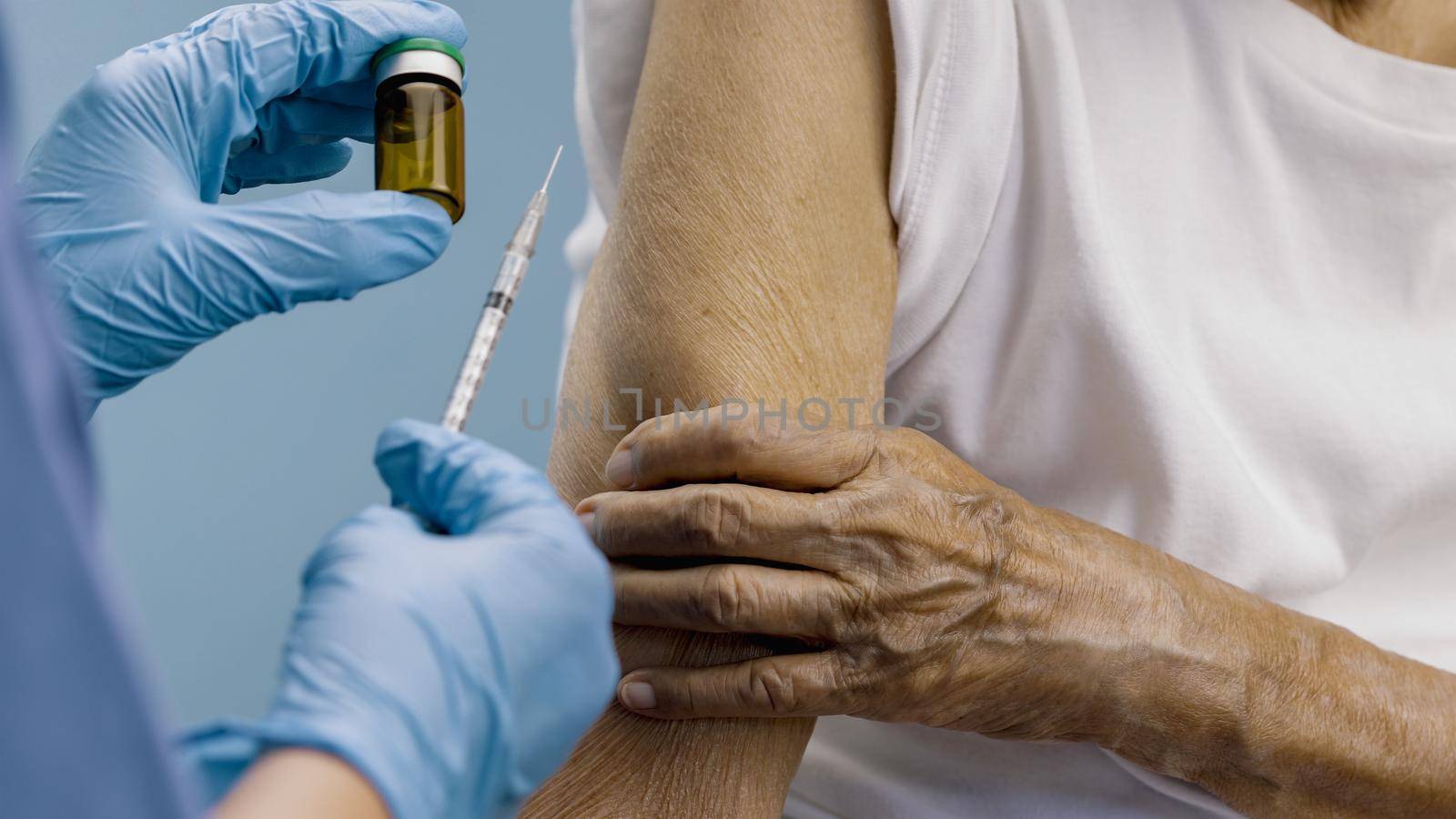Doctor doing vaccine injection to senior woman.