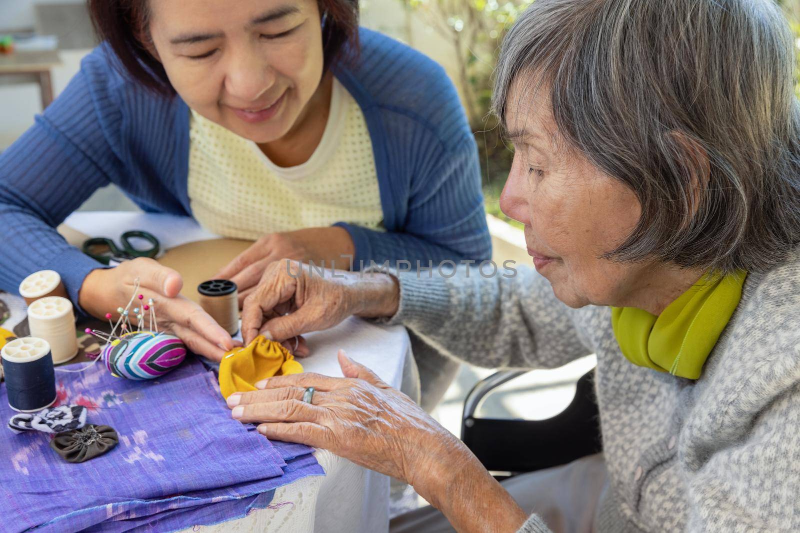 Elderly woman and daughter in the needle crafts occupational therapy for Alzheimer’s or dementia