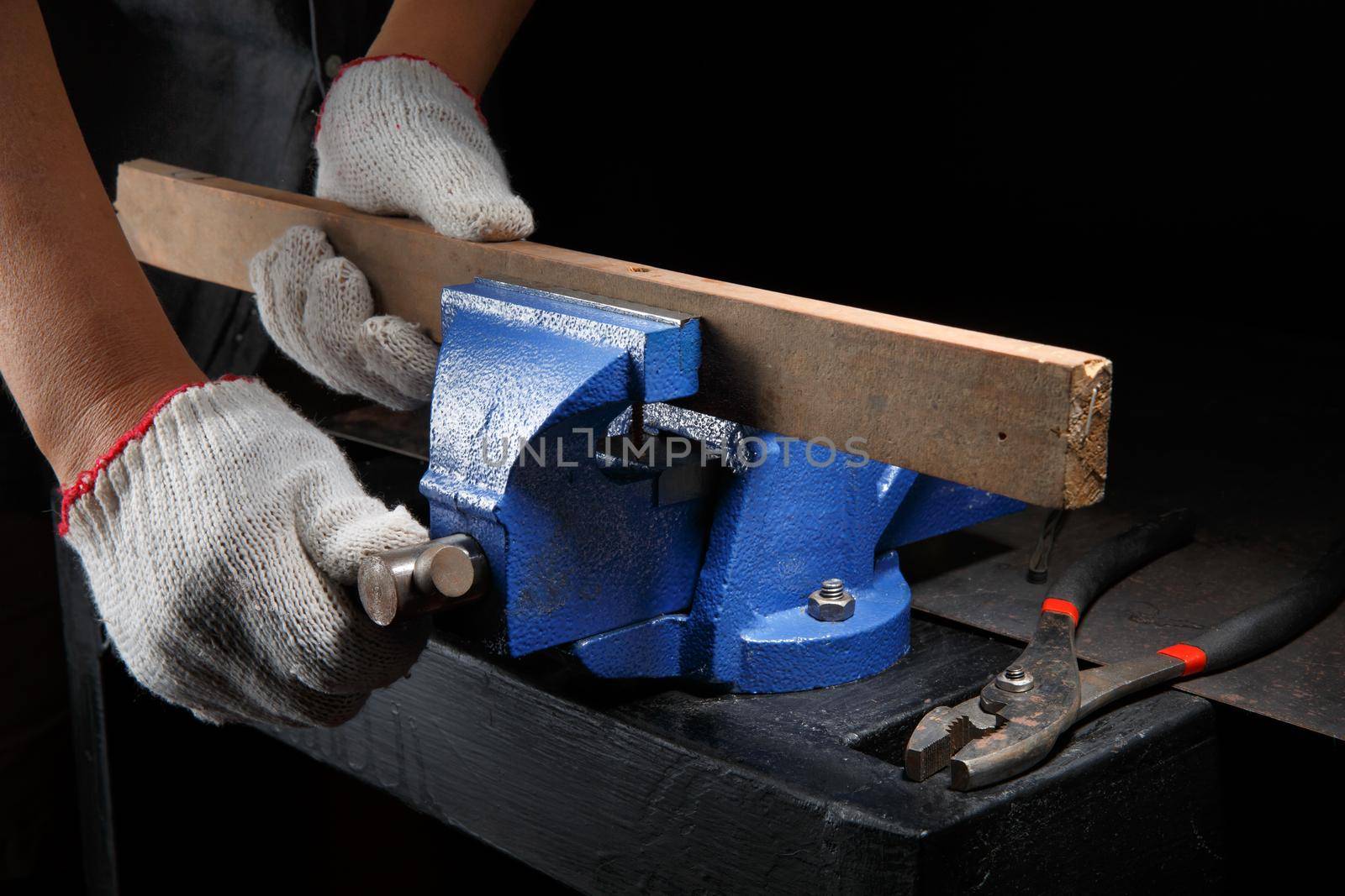 Closeup workers hands on a  wooden plank locked in the iron vise by toa55