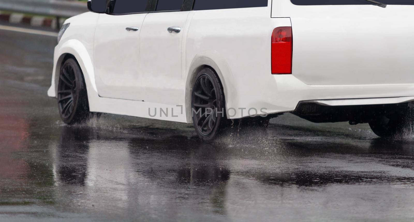 Heavy rain and puddles on the road cause skidding or sliding of a cars tires across a wet surface by toa55