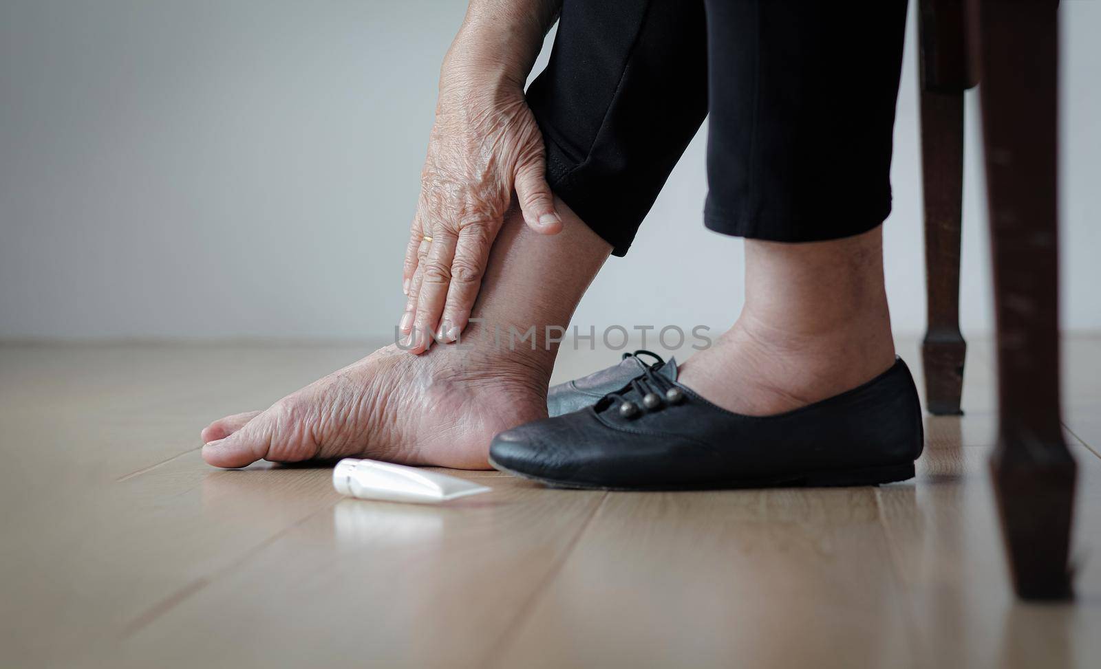 Elderly woman putting cream on swollen feet before put on shoes by toa55