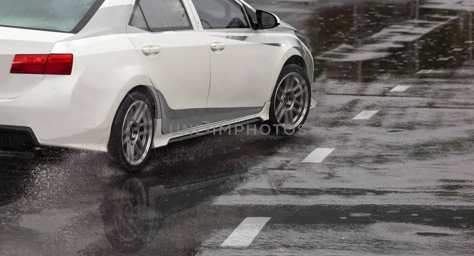 Heavy rain and puddles on the road cause skidding or sliding of a cars tires across a wet surface