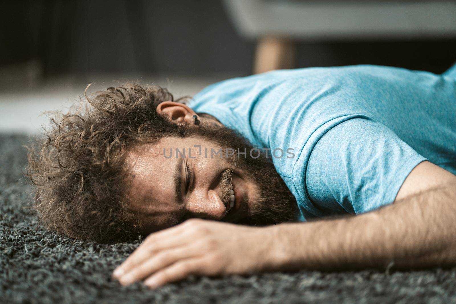 funny guy lying laughing on the floor on a fleece carpet, rest after exercise, relax, have fun, face close-up . High quality photo