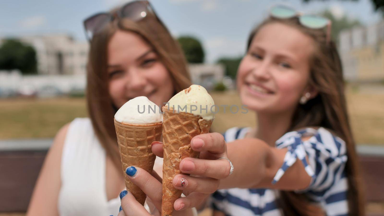 Two girls are presenting ice cream to the viewer