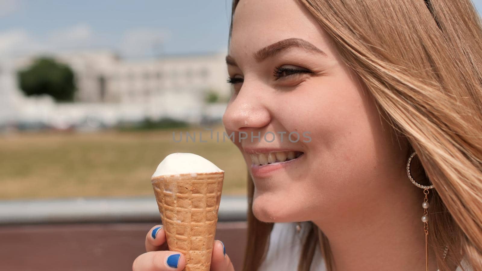 The girl eats an ice cream cone on the street of the city. by DovidPro
