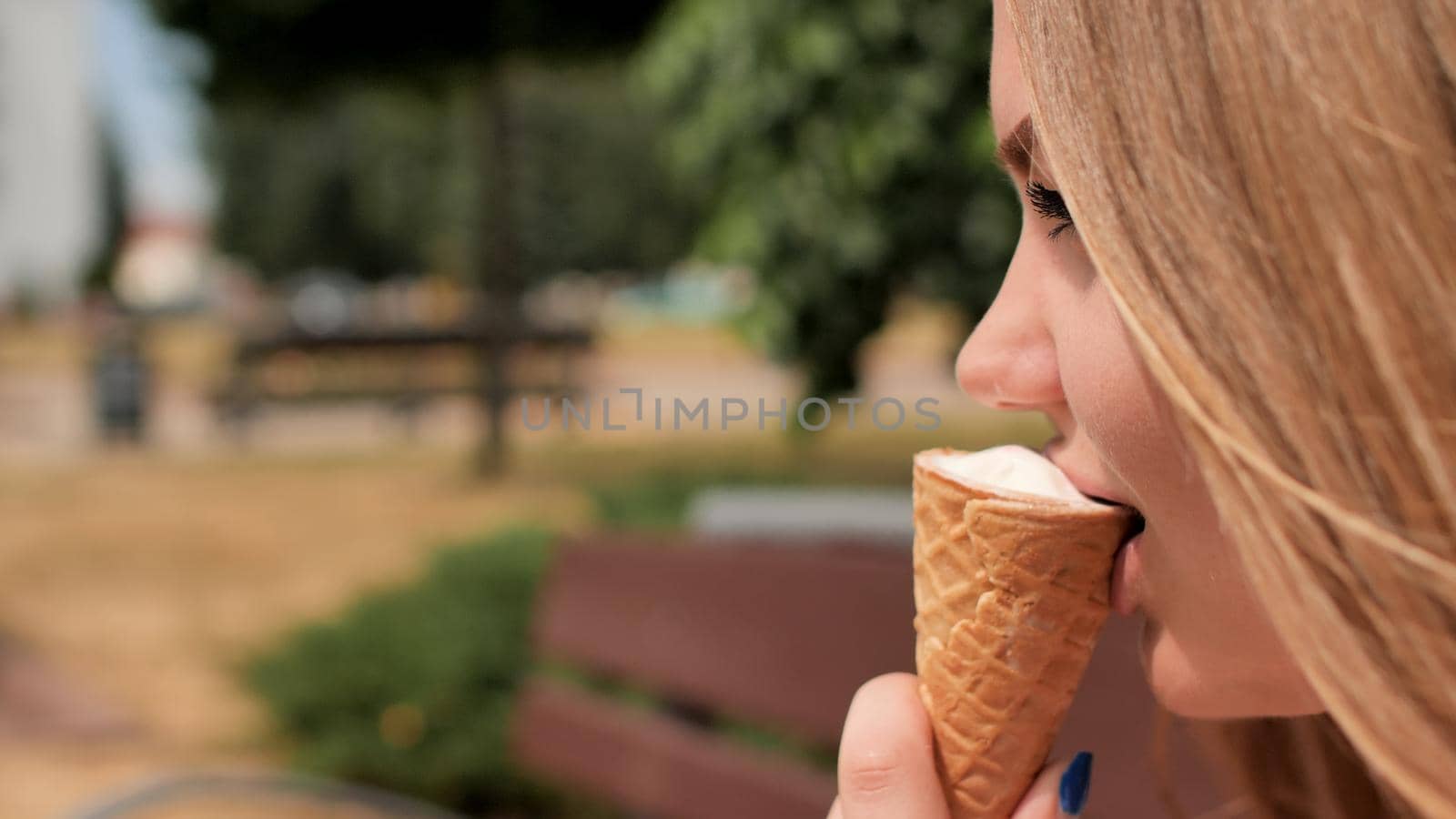 The girl eats an ice cream cone on the street of the city