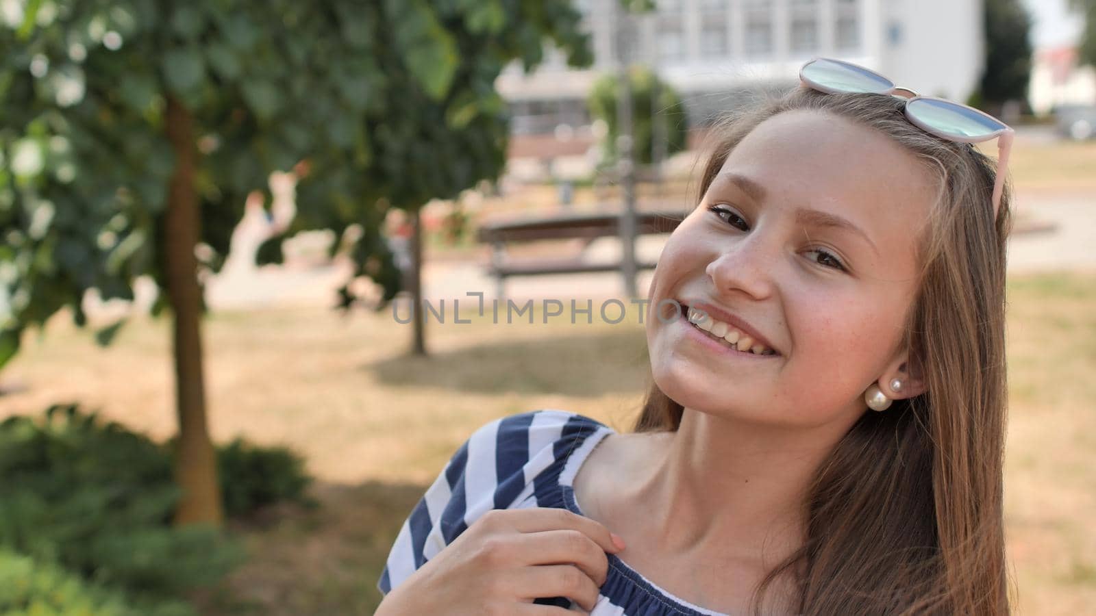 Portrait of a young smiling girl in the park on a summer day. by DovidPro