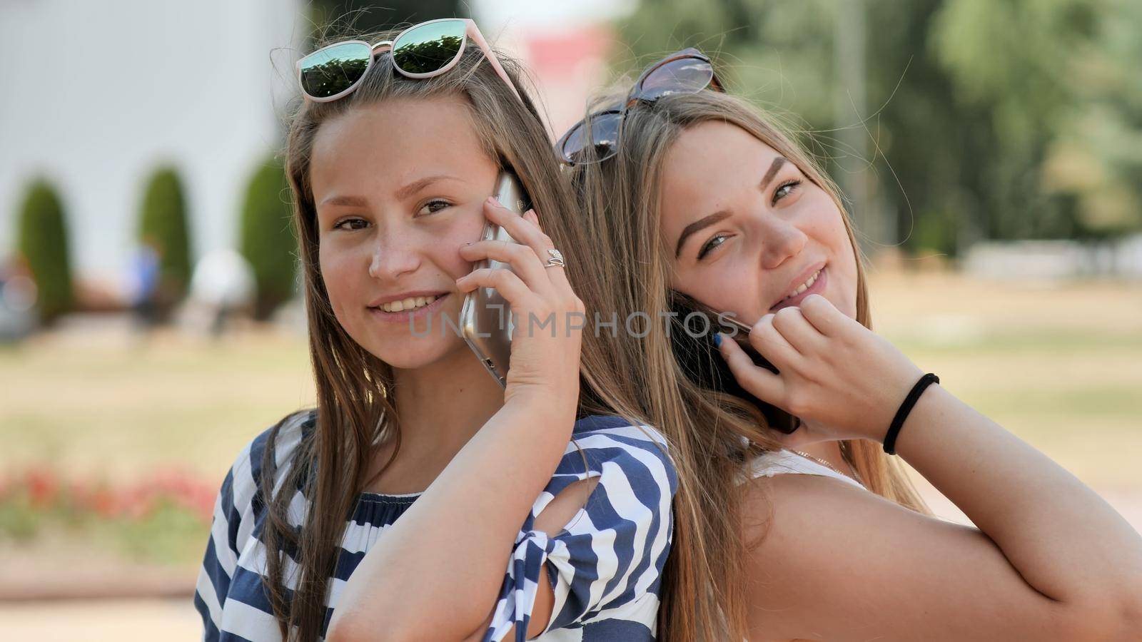 Two young girls talking on the phone on a summer day