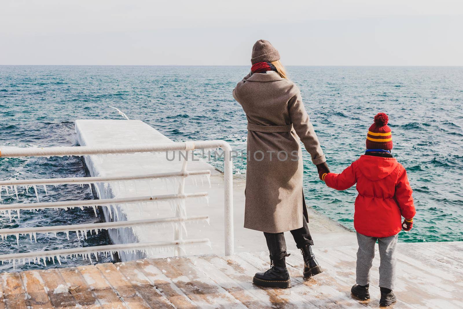 Mother and son on a pier at the sea in winter by Syvanych