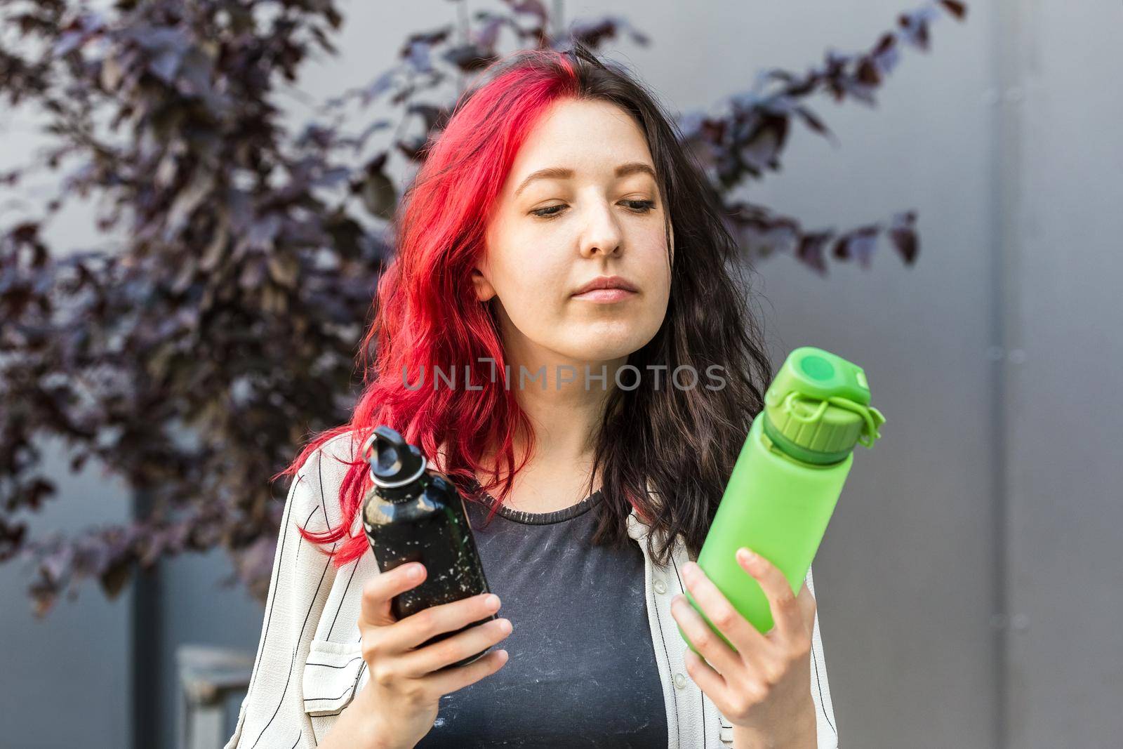 Woman choosing between two types of water bottles by Syvanych