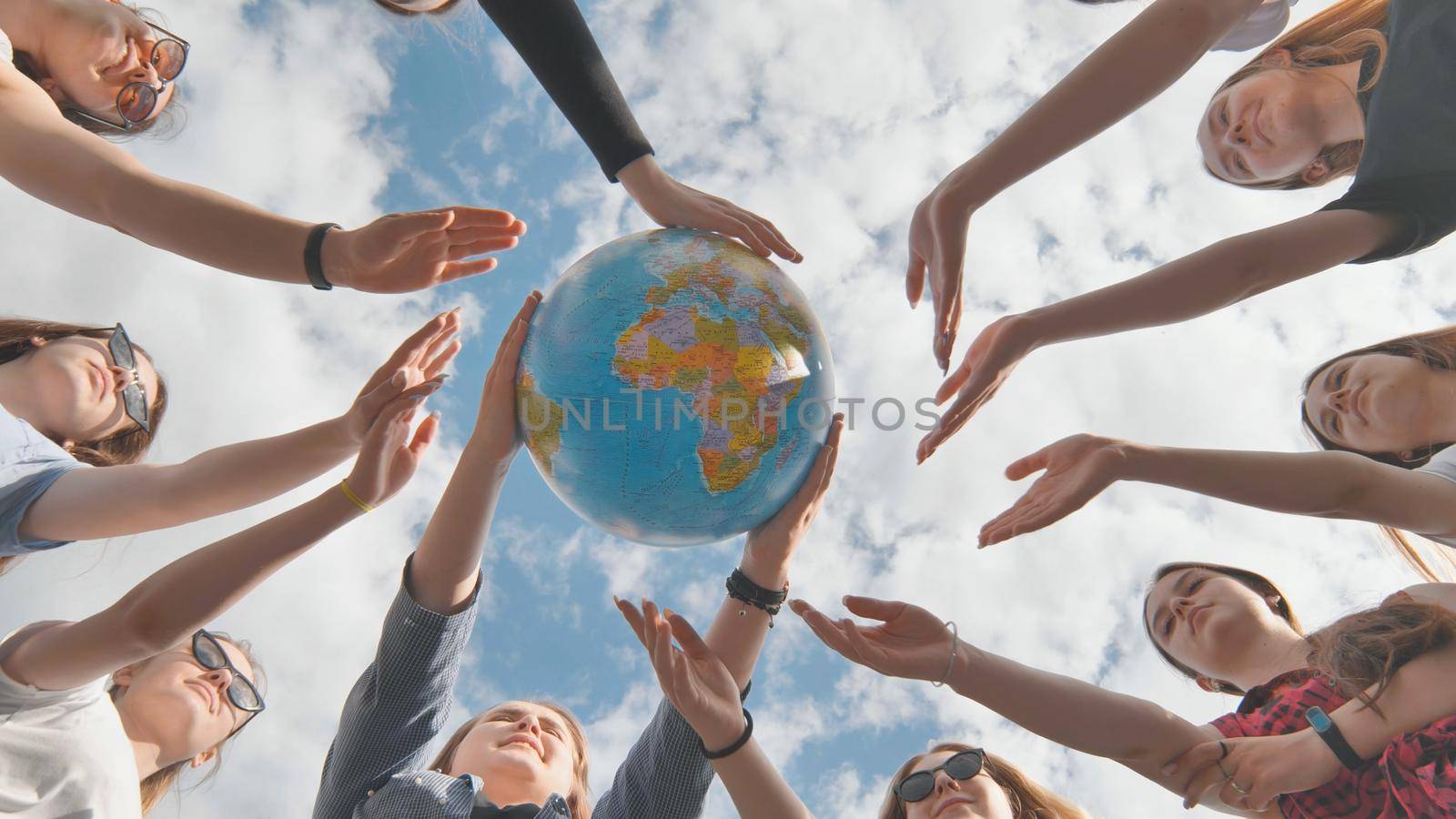 Earth conservation concept. 11 girls hug the earth globe with their hands