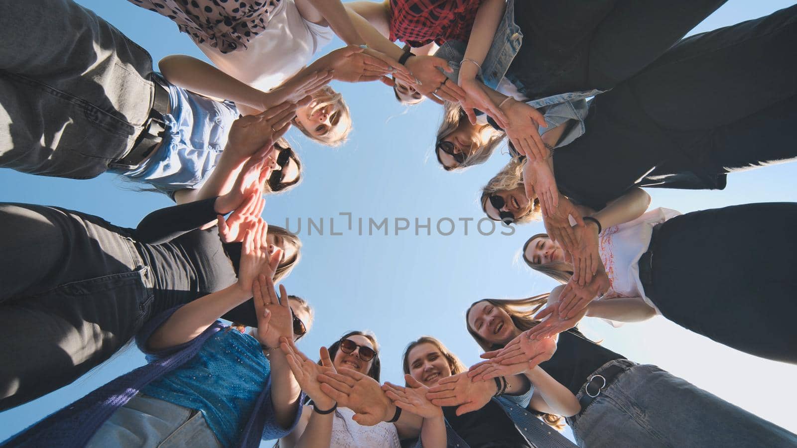 A group of girls makes a circle from their palms hands. by DovidPro