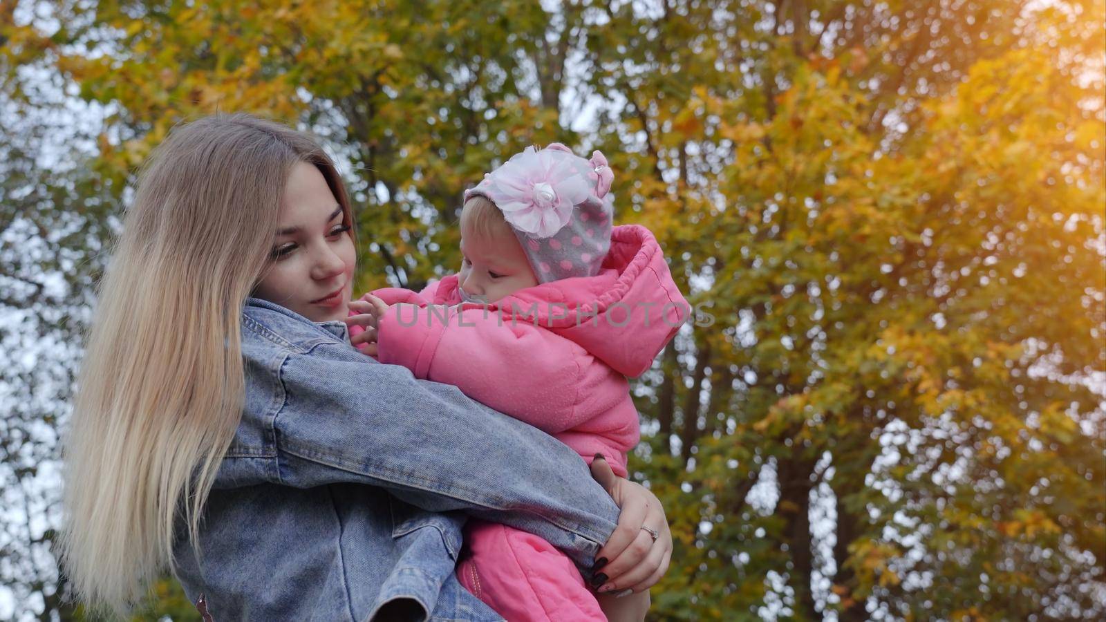 Young mother with her daughter on a warm autumn evening