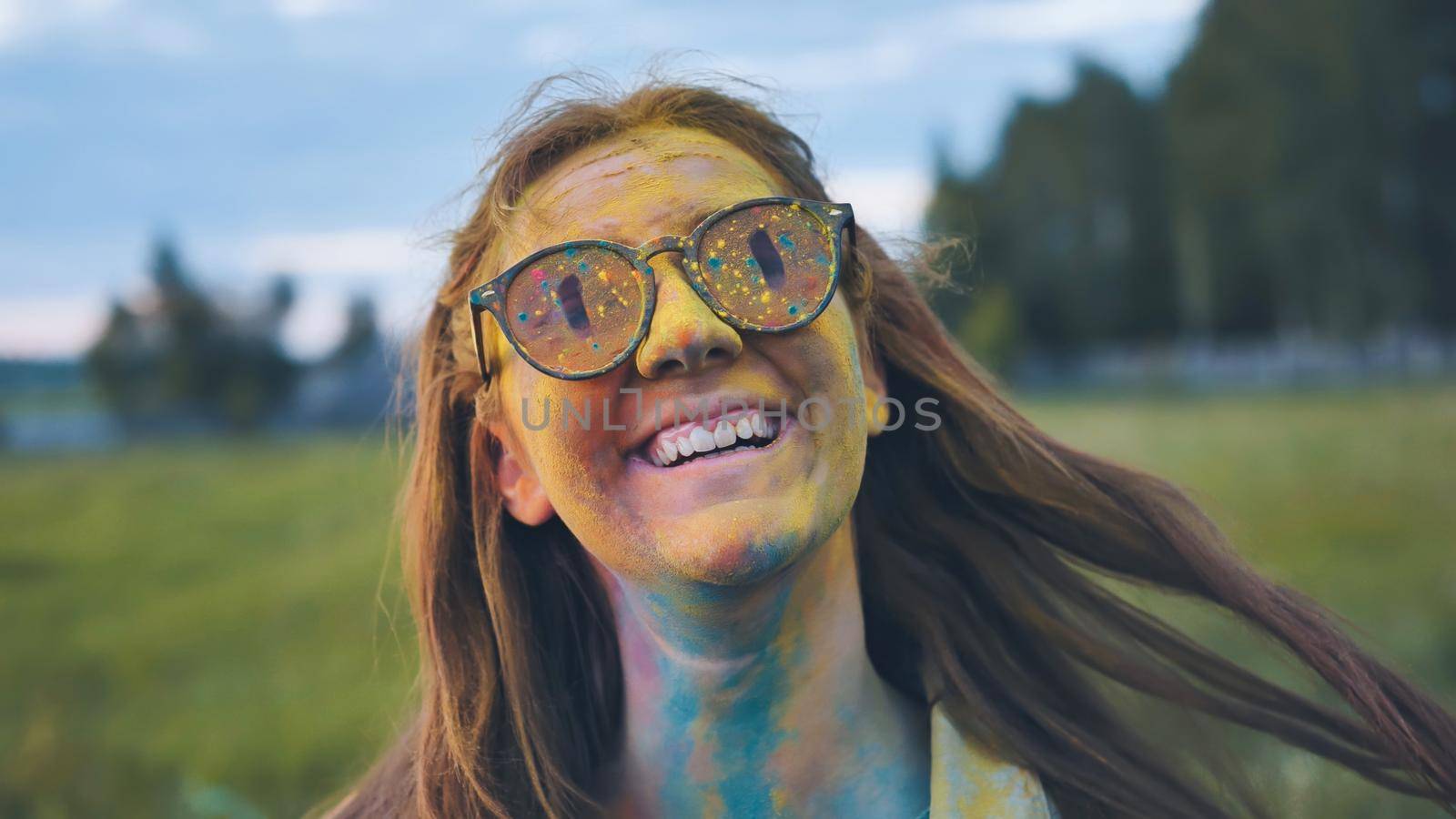 Cheerful girl posing smeared in multi-colored powder