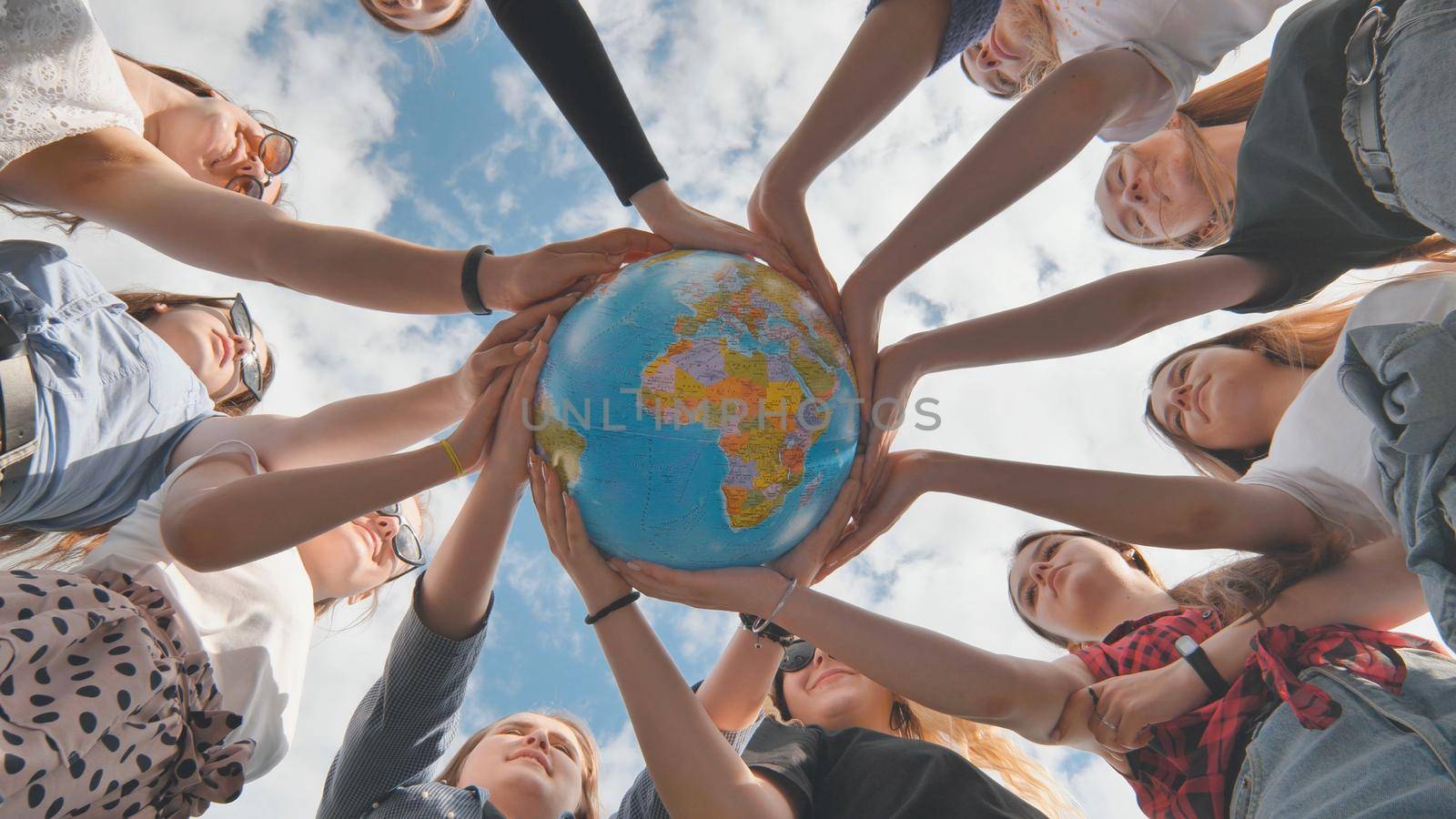 Earth conservation concept. 11 girls hug the earth globe with their hands