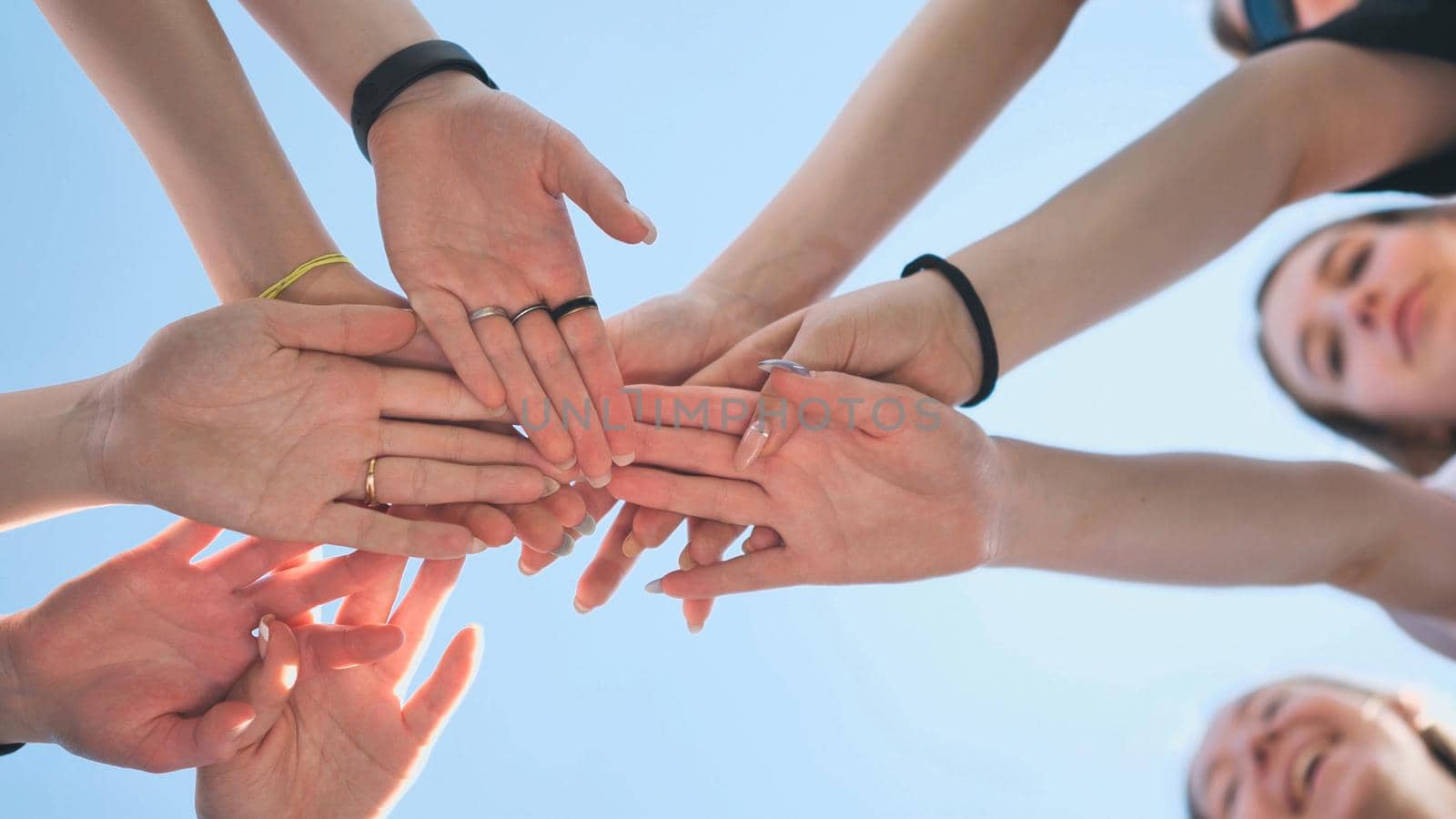 Cheerful girls join hands together as a sign of unity and joint successful work. Teamwork stacking hand concept