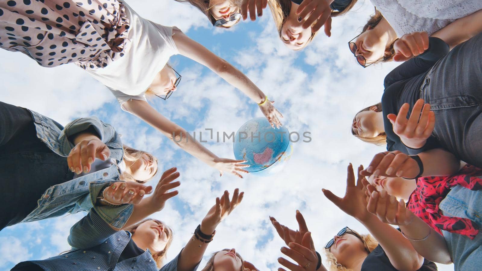 Female student girls standing in a circle toss the world globe up