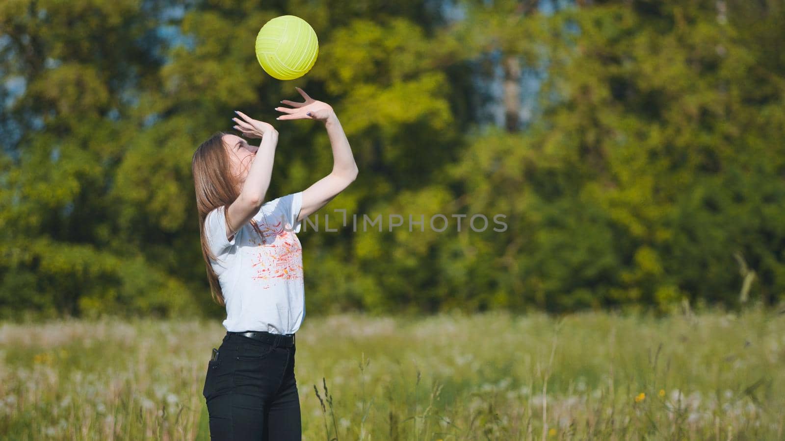Two girlfriends play volleyball in the meadow