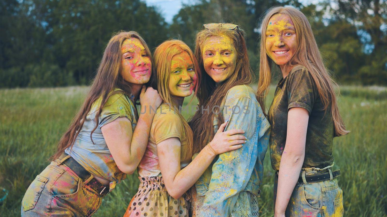 Cheerful girls posing smeared in multi-colored powder