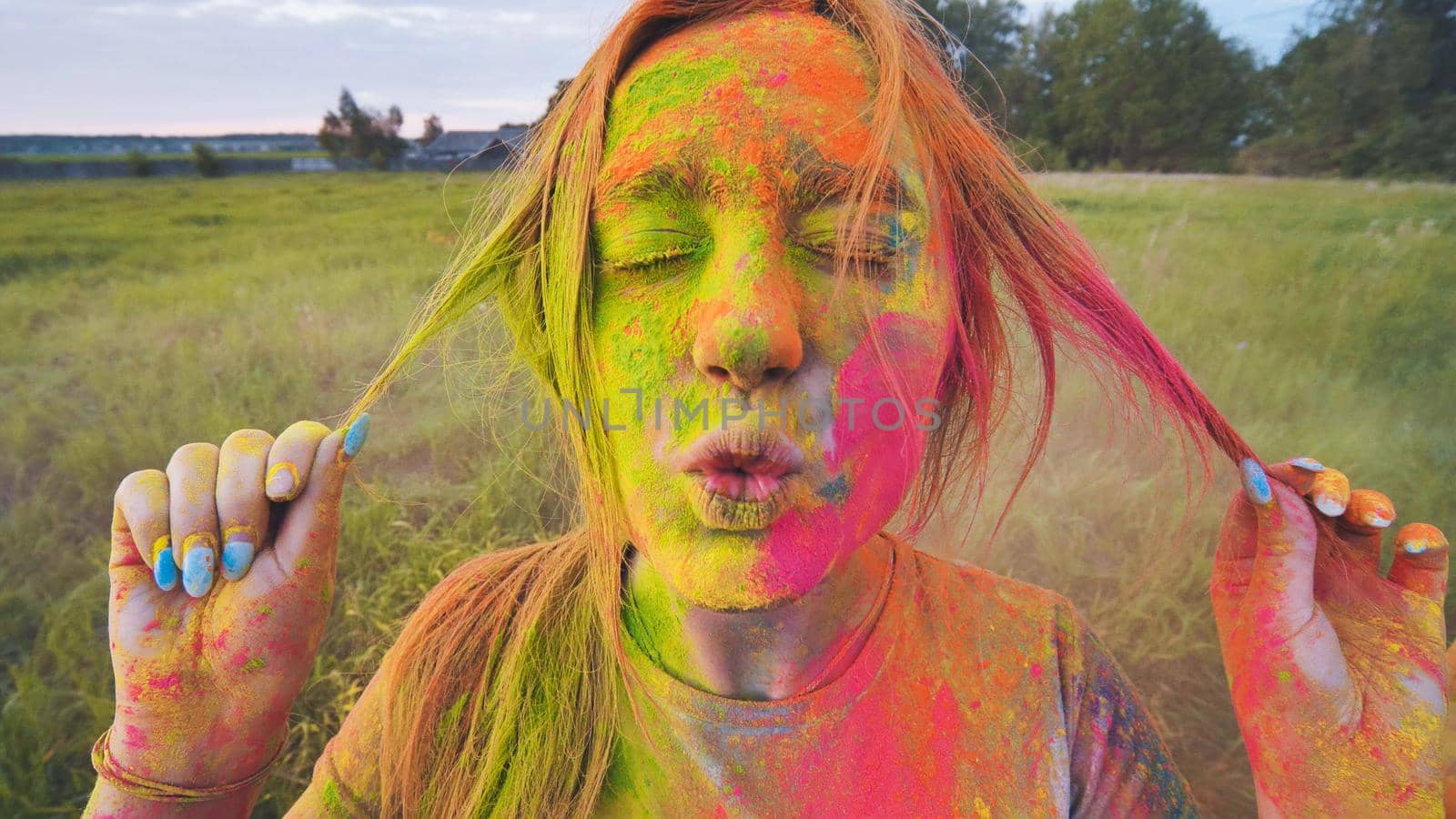 Cheerful girl posing smeared in multi-colored powder. Close-up face