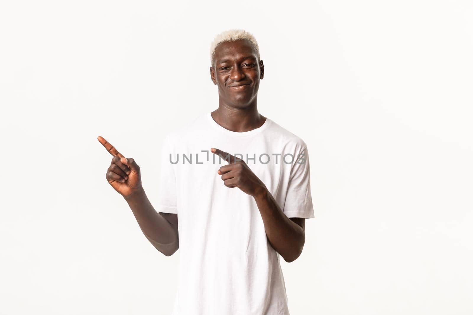 Portrait of young african american blond guy with smug face, smirking and pointing upper left corner pleased, standing white background by Benzoix