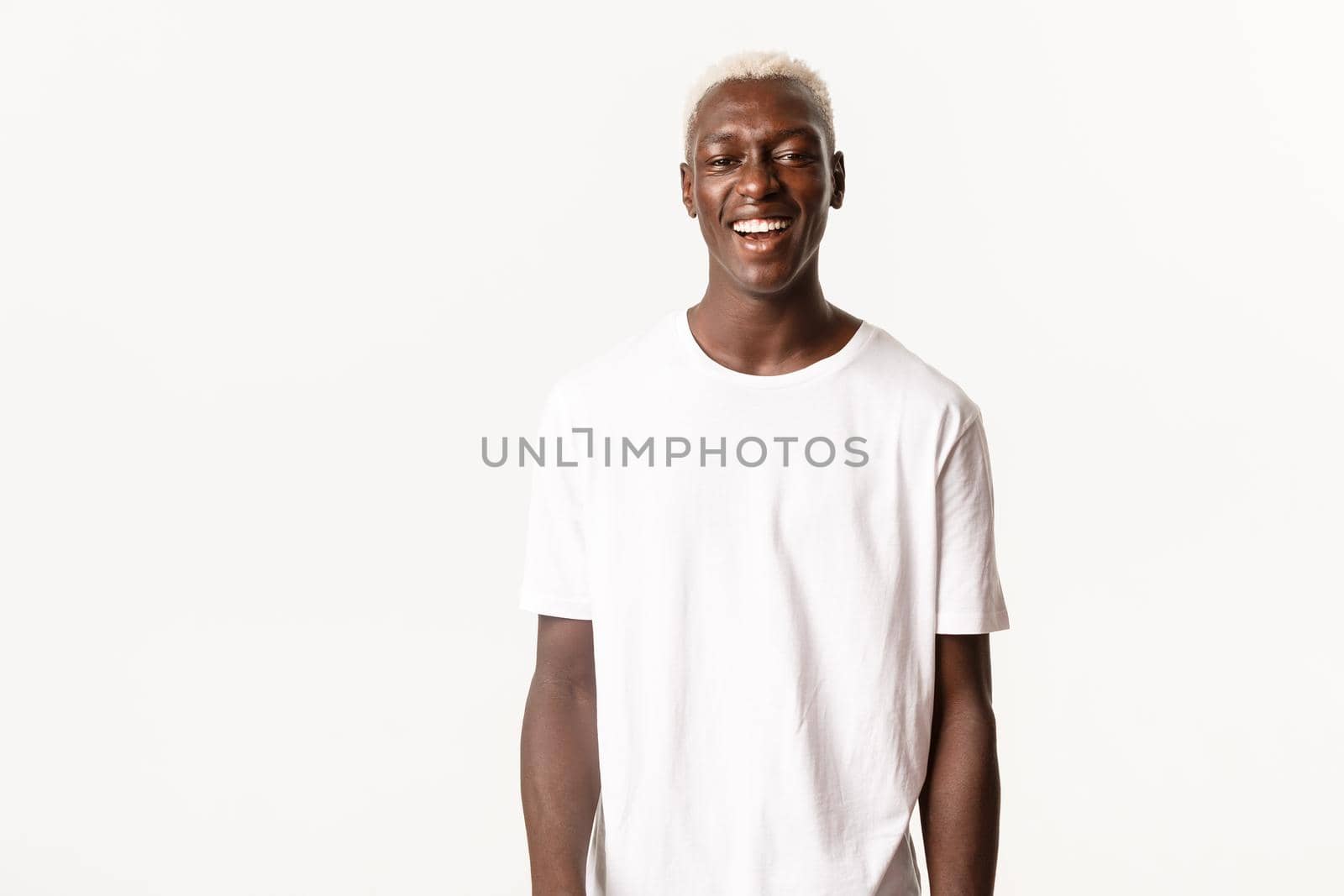 Portrait of carefree handsome blond guy, laughing happy at looking upbeat, standing over white background by Benzoix