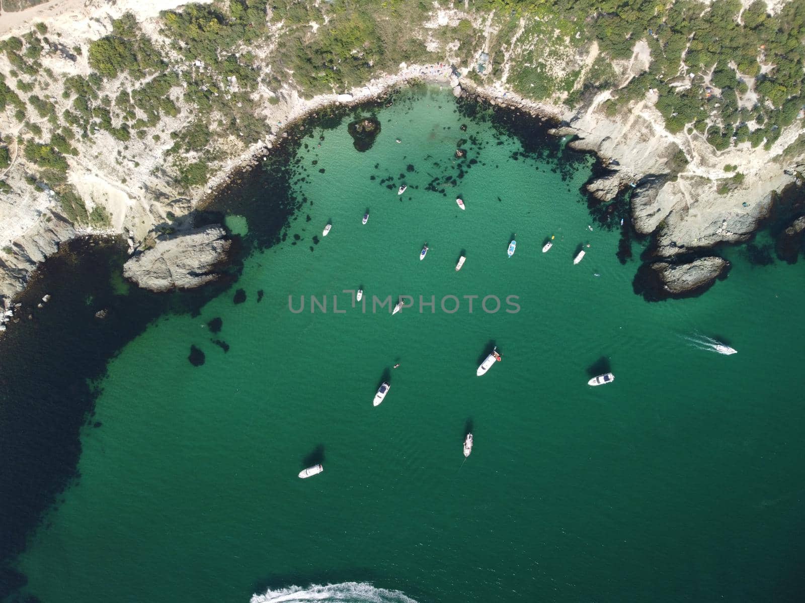 Sea landscape with rocky coastline on sunset time with cloudy sky. Yachts in the Sea on a background of rocky shores. The concept of perfect place for summer travel and rest.