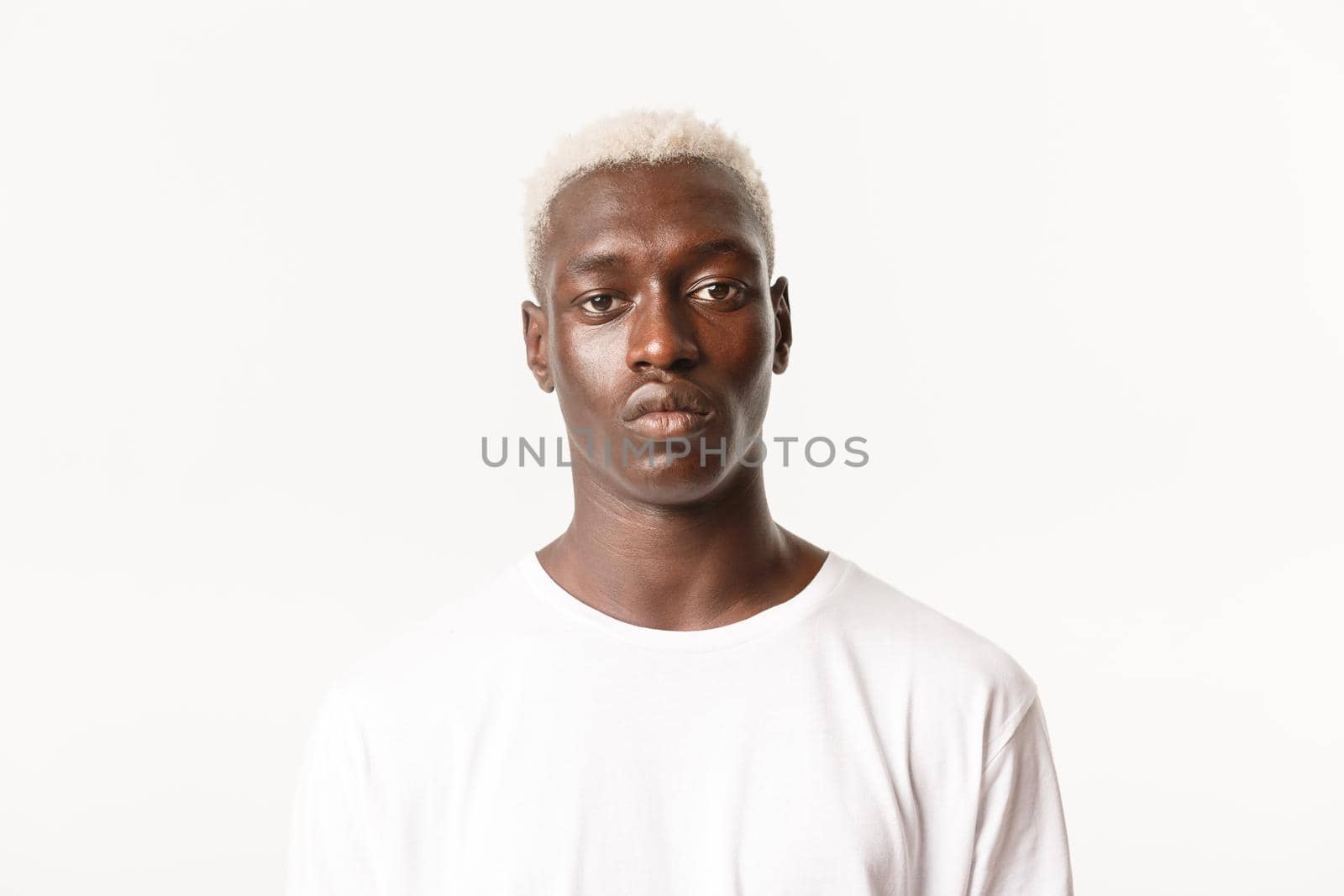 Close-up of serious handsome african-american blond stylish guy, looking at camera determined and calm, standing white background.