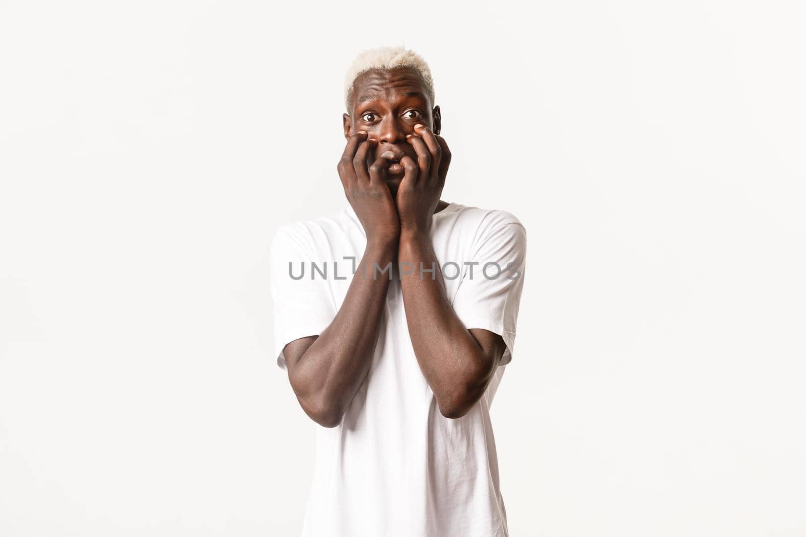 Portrait of thrilled and tempted african-american blond guy, trembling from excitement, standing white background.
