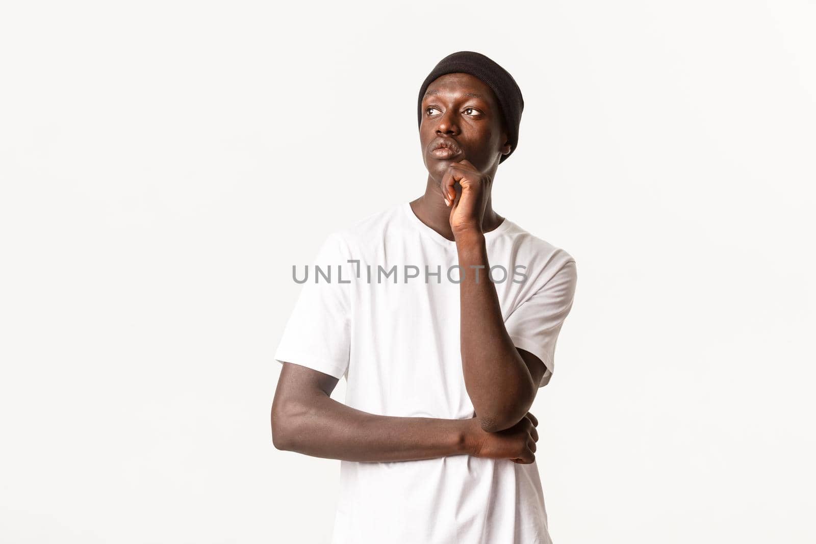 Portrait of thoughtful stylish african-american man in beanie, looking left and pondering, making choice, standing white background.