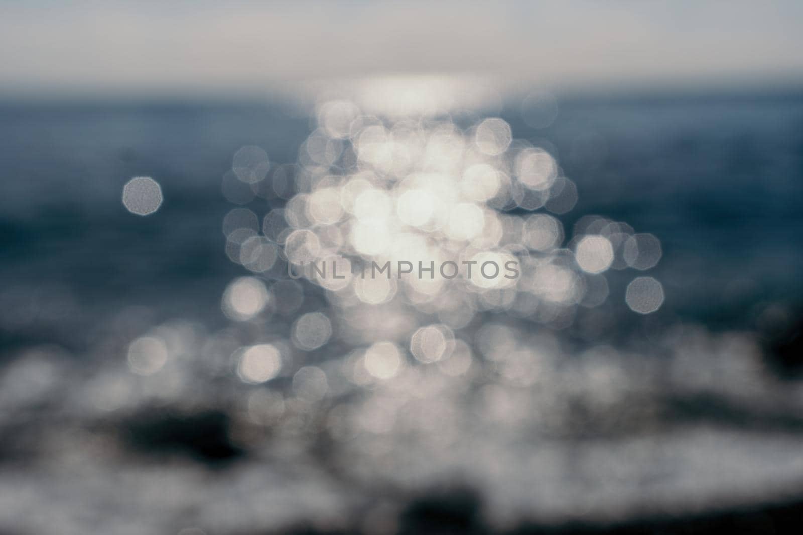 Abstract nature summer or spring ocean sea background. Small waves on water surface in motion blur with bokeh lights from sunrise.