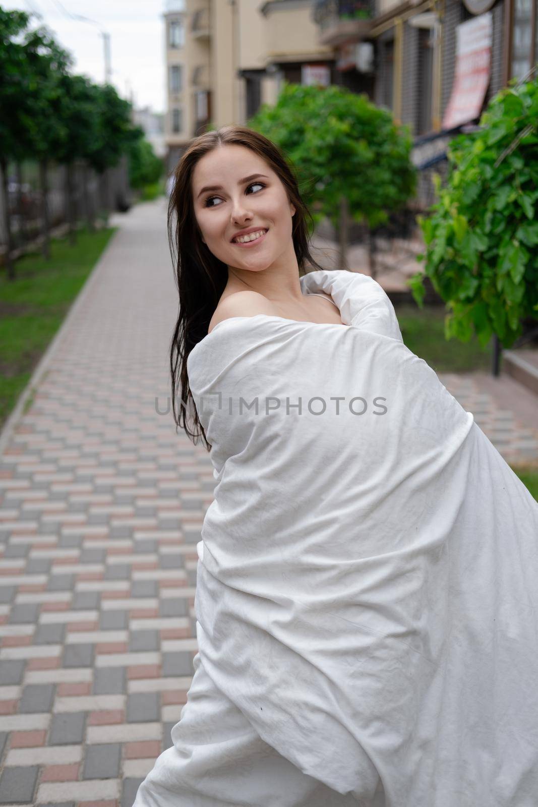 pretty brunette woman in white blanket outdoors. crazy rebel millennial girl.