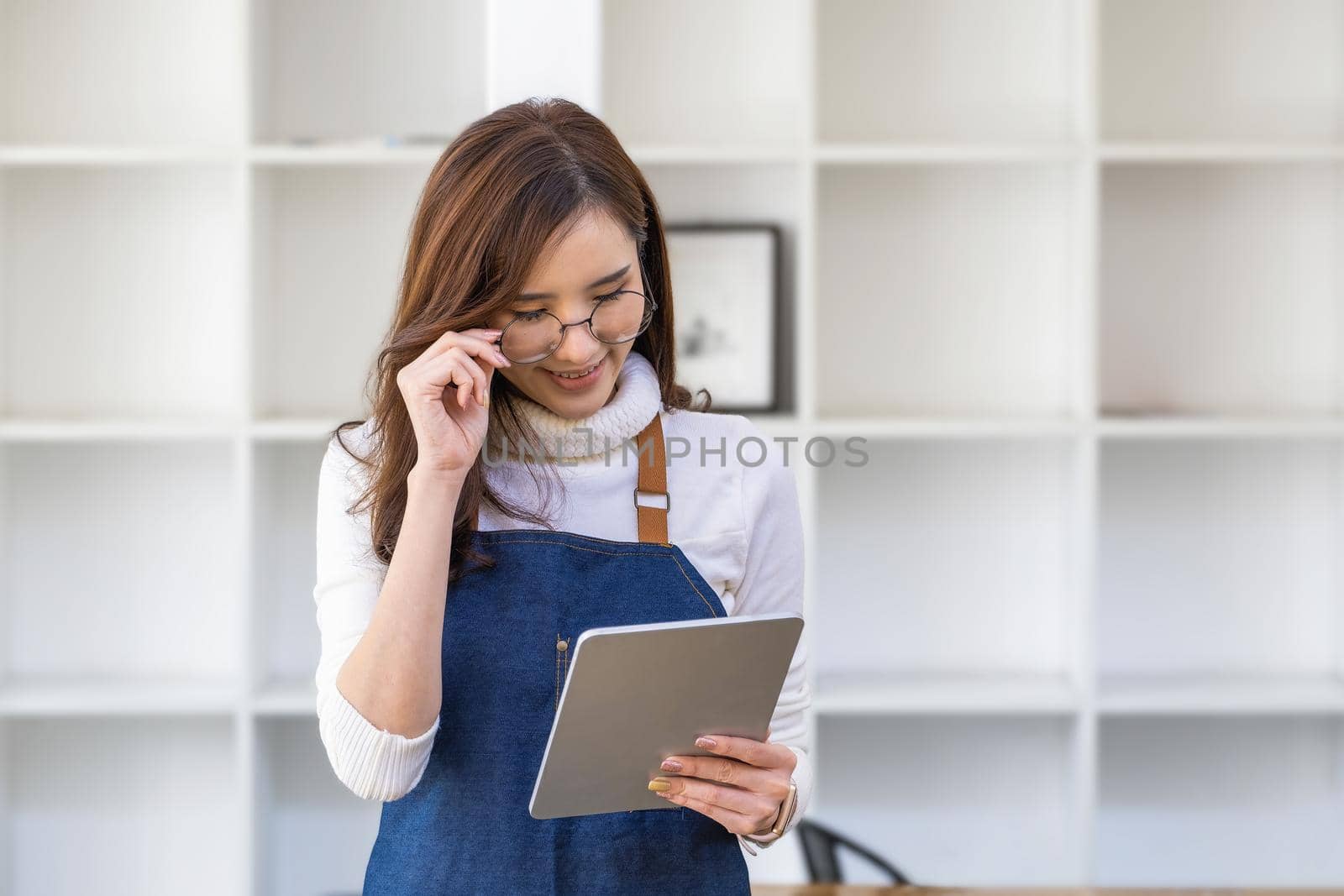 Startup small business owners, sme entrepreneurs smiling and holding a tablet looking at their own business income. by Manastrong