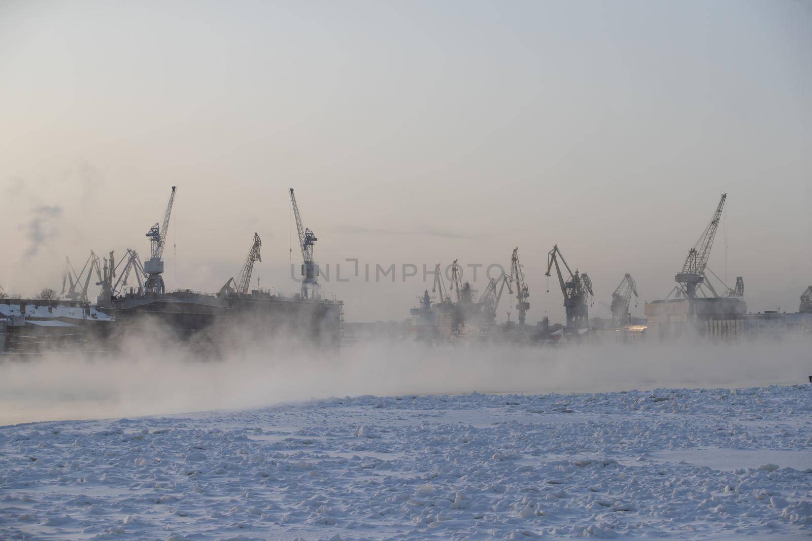 The construction of nuclear icebreakers, cranes of of the Baltic shipyard in a frosty winter day, steam over the Neva river, smooth surface of the river. High quality photo
