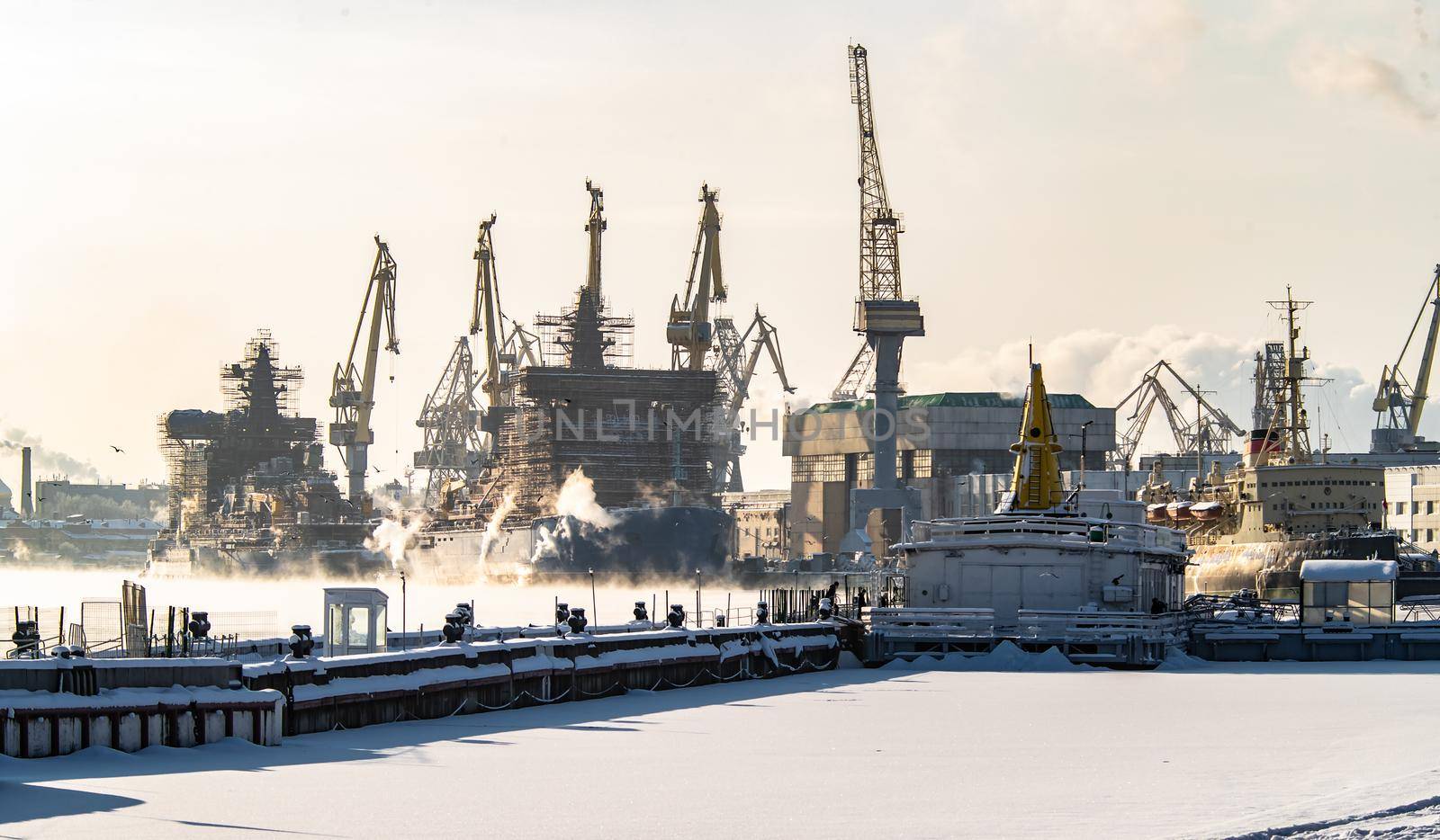The construction of nuclear icebreakers, cranes of of the Baltic shipyard in a frosty winter day, steam over the Neva river, smooth surface of the river. High quality photo