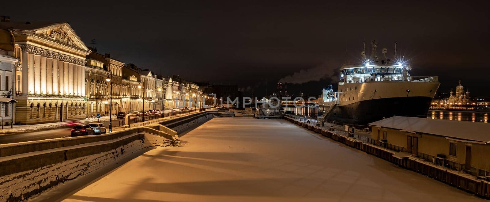 The panoramic footage of the winter night city Saint-Petersburg with picturesque reflection on water, big ship moored near Blagoveshchensky bridge, English embankment, cathedral on background. High quality photo