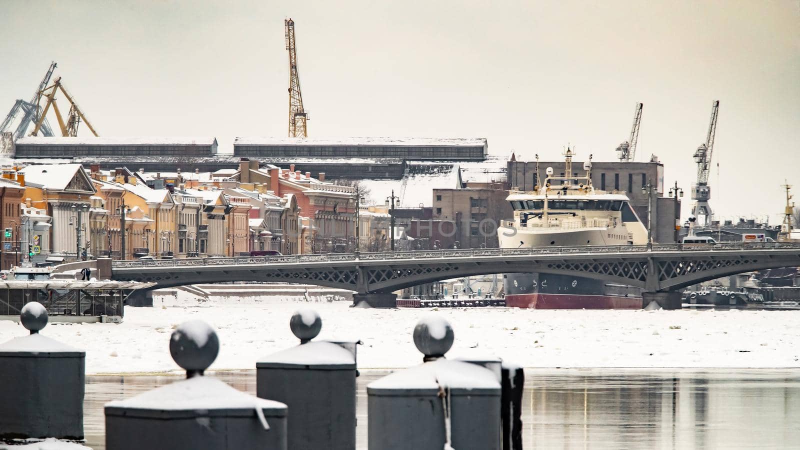 The panoramic image of the winter city Saint-Petersburg with picturesque reflection on water at sunset, big ship moored near Blagoveshchensky bridge, English embankment. High quality photo