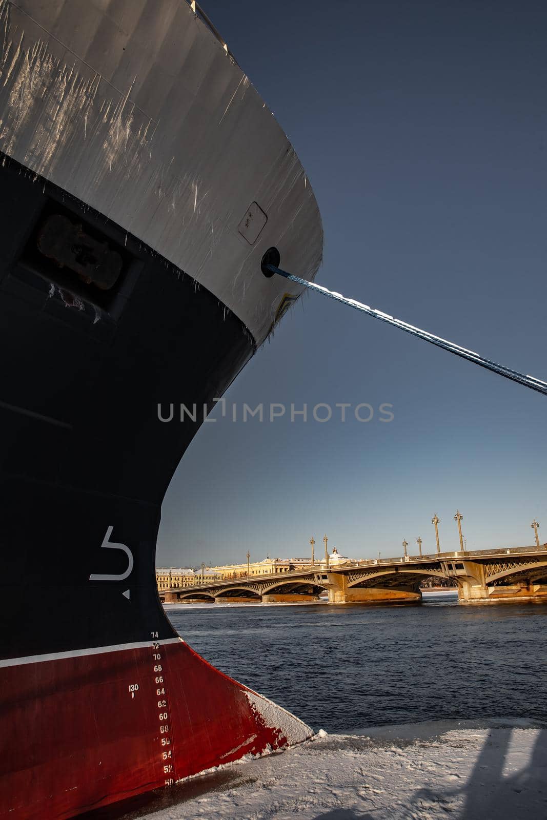 The panoramic view of the winter city Saint-Petersburg at sunny day, big ship moored near Blagoveshchensky bridge, mooring lines, thick ropes, river and bridge on background. High quality photo