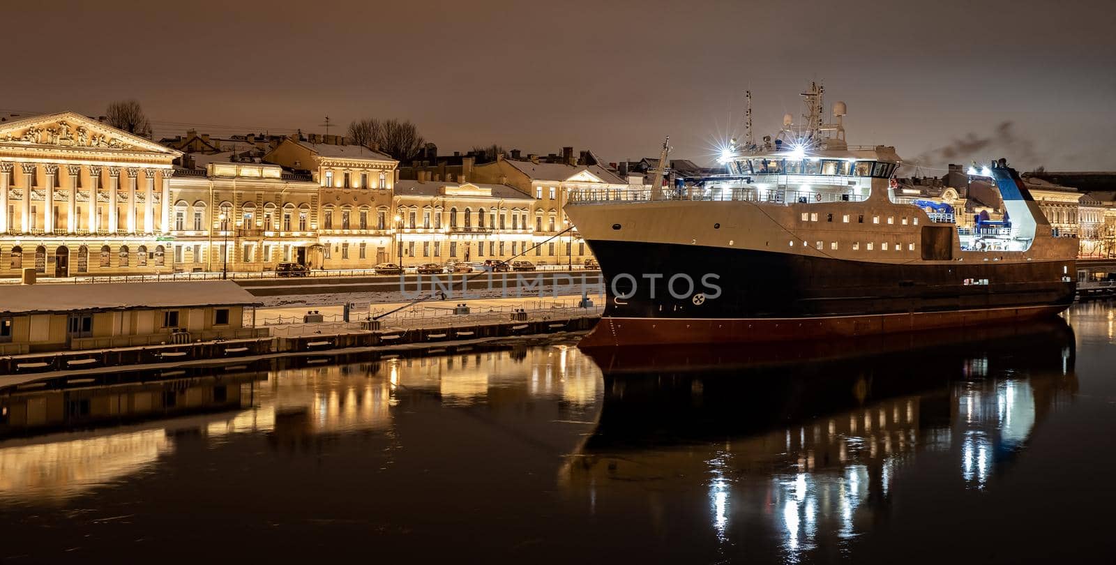 The panoramic footage of the winter night city Saint-Petersburg with picturesque reflection on water, big ship moored near Blagoveshchensky bridge or lieutenant Schmidt, Isaac cathedral on background. High quality photo
