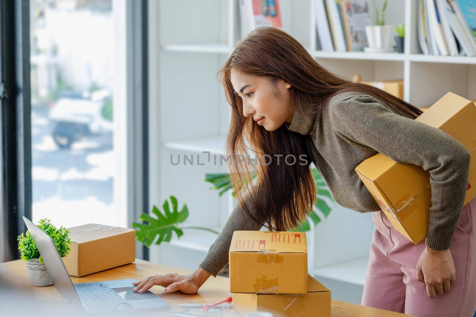 Work from home. happy women selling products online Start a small business owner by using laptop computer to calculate prices and prepare for postage. by Manastrong