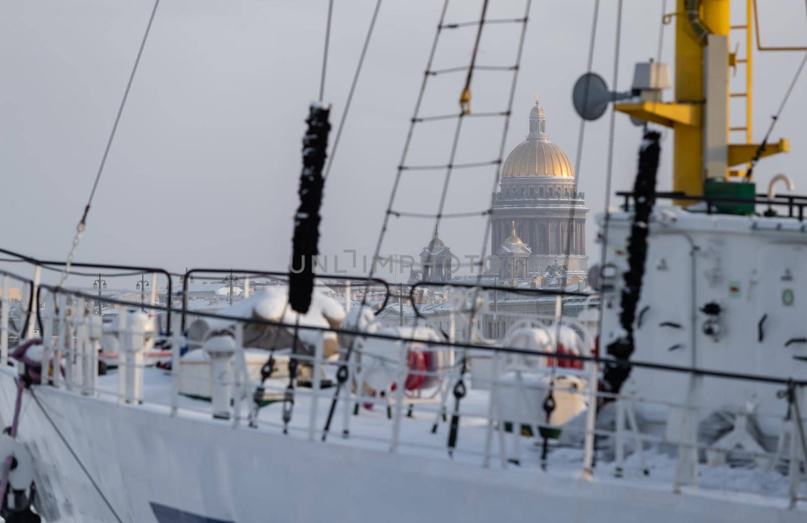 The golden dome of Isaac cathedral through old moored sail boat at frosty day, Winter landscape of St. Petersburg. High quality photo