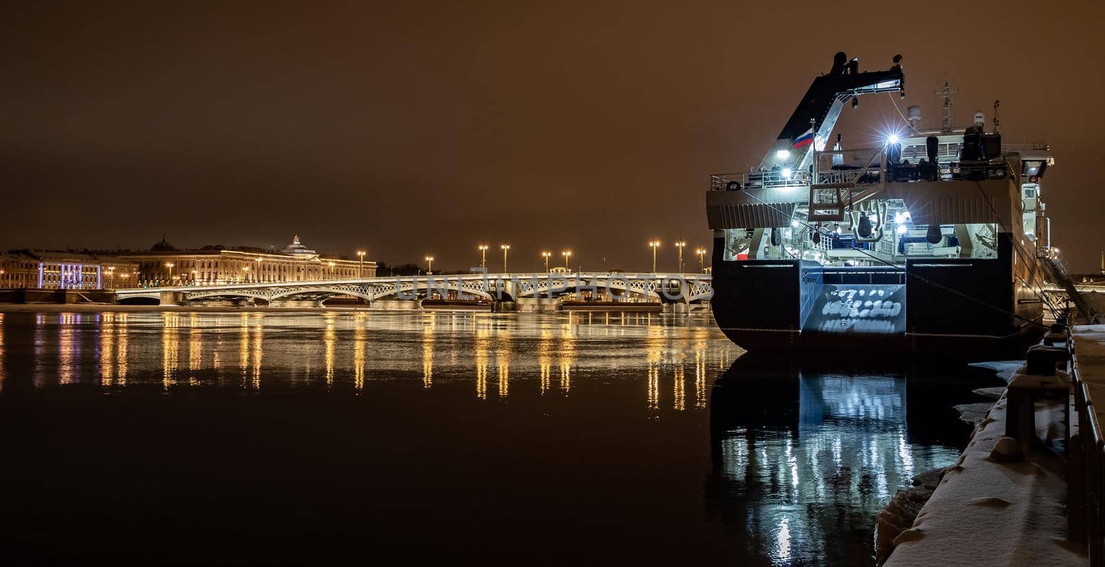 The panoramic footage of the winter night city Saint-Petersburg with picturesque reflection on water, big ship moored near Blagoveshchensky bridge or lieutenant Schmidt, Isaac cathedral on background. High quality photo