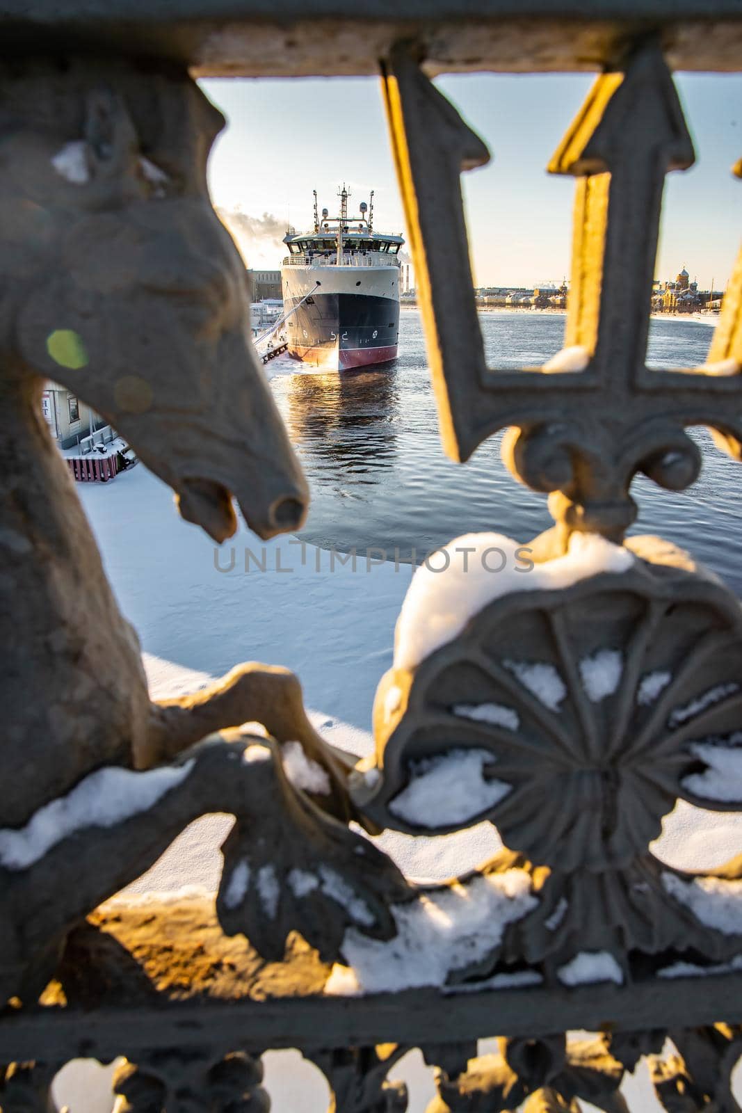 The big ship moored near English embankment through the railing of the bridge Blagoveshchensky, the winter city Saint-Petersburg, the lights of a sun, mooring lines, thick ropes. High quality photo