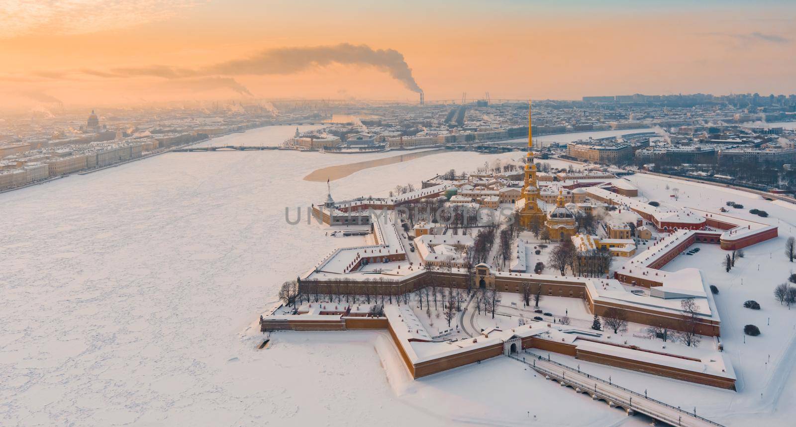 Drone point of view of winter St. Petersburg at sunset, frozen Neva river, steam over city, Peter and Paul fortress, car traffic on Trinity bridge, rostral columns, Palace drawbridge, panoramic view. High quality photo